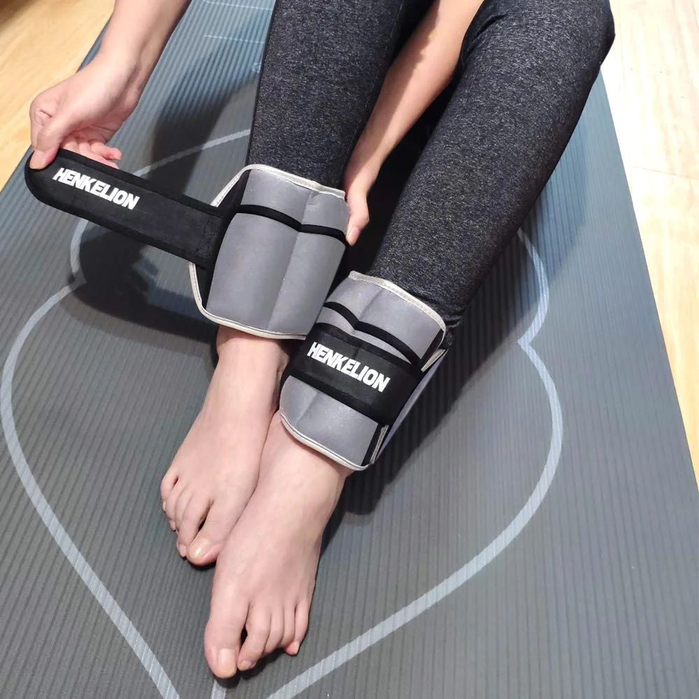 A gray Henkelion ankle weight being fastened around an ankle on a yoga mat