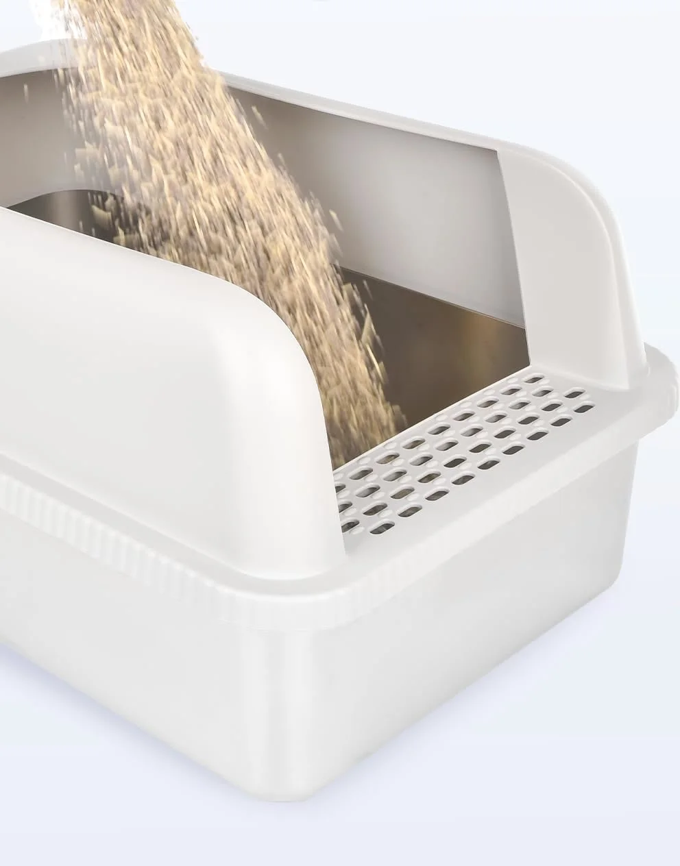 Litter being poured into the stainless steel pan of the Henkelion litter box, with the perforated step at the front of the enclosure.